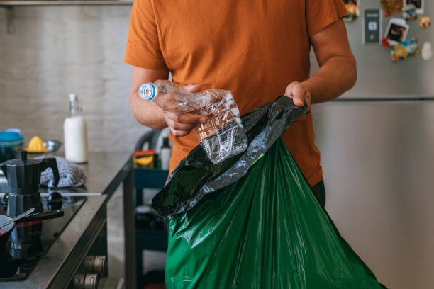 Handsome young man holding green garbage bag and plastic bottle Handsome young man holding green garbage bag and plastic bottle